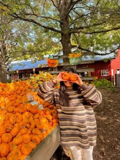 a woman standing next to a pile of pumpkins