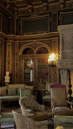 an ornately decorated living room with chairs and bookshelves on the wall, in front of a fireplace