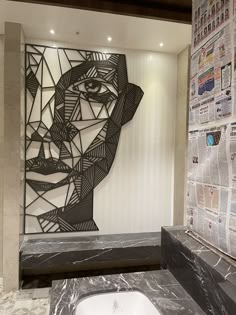 a bathroom with a sink, mirror and newspaper paper on the wall behind it that has a face made out of newspapers