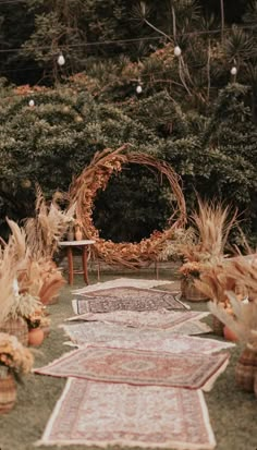 an outdoor area with rugs and plants on the ground, surrounded by greenery