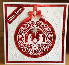 a red and white christmas ornament on a card with a ribbon around it