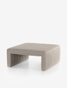 an upholstered coffee table with wavy lines on the top and bottom, in grey