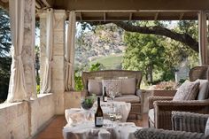 an outdoor patio with wicker furniture and white table cloths, wine bottle on the table