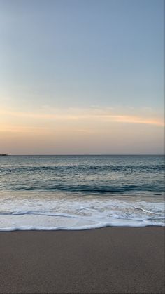 an empty beach with waves coming in to shore