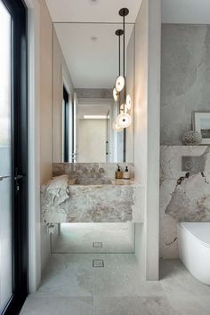 a bathroom with marble walls and flooring, along with a large mirror on the wall