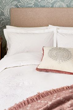 a bed with pillows and blankets on top of it next to a wooden headboard