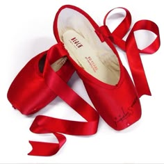 a pair of red ballet shoes with a ribbon tied around them