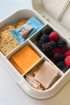 a bento box filled with crackers, fruit and cheese