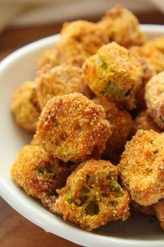 a white bowl filled with fried food on top of a wooden table