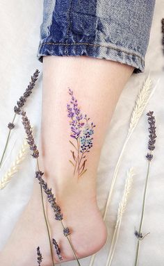 a woman's foot with purple flowers on it and some lavenders in the foreground