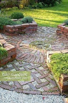 a garden area with stones, grass and plants in the center is surrounded by gravel