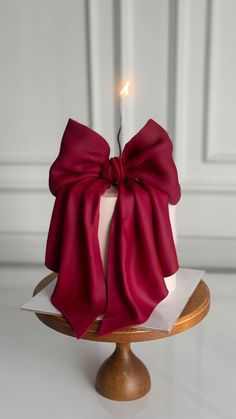 a candle with a red bow on it sitting on top of a cake platter