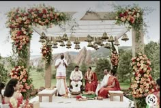 a group of people sitting on top of a white bench under a gazebo covered in flowers