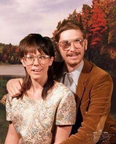 a man and woman sitting next to each other in front of a painting on the wall