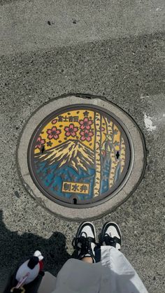 a manhole cover on the ground with his feet propped up in front of it