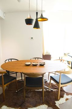 a dining room table with chairs and a cow hide rug on the floor in front of it