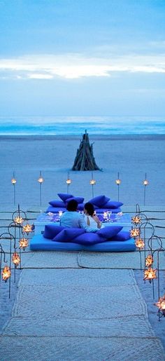 an outdoor seating area with candles on the beach