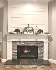 the fireplace is decorated with pumpkins and greenery on it's mantel