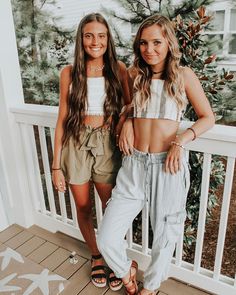 two girls standing on a porch with their arms around each other and one is wearing sandals