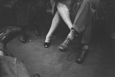 a black and white photo of people sitting on a bus with their feet propped up