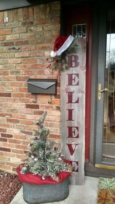 a sign that says believe on the side of a brick building next to a christmas tree