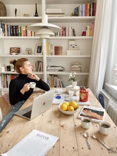 a woman sitting at a table with her laptop and coffee cup in front of her