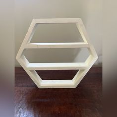 a white hexagonal shelf sitting on top of a wooden floor next to a wall