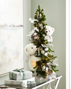 two white teddy bears sitting on top of a christmas tree