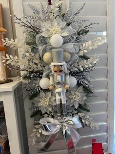 a christmas tree decorated with silver and white decorations, including a nutcracker ornament