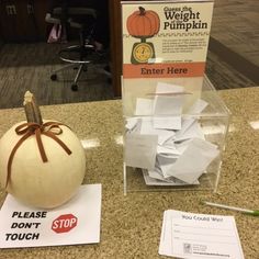 a white pumpkin sitting on top of a counter next to a sign that says please don't touch