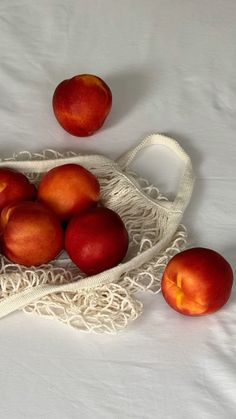 a white cloth bag filled with peaches on top of a white tablecloth covered table