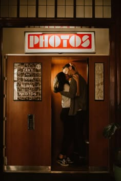 a man and woman are kissing in front of a photo shop sign on the door