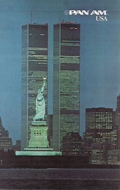 the statue of liberty stands in front of two tall buildings with lights on each side