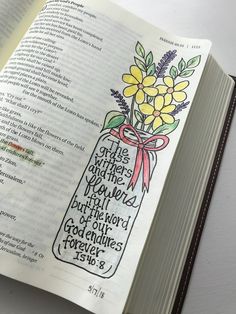 an open bible with flowers in a mason jar