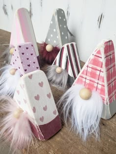 small wooden gnomes are lined up on a table with hearts and feathers attached to them