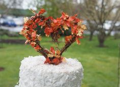 a white cake with leaves on top in the shape of a heart shaped tree branch