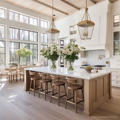 a large kitchen with white cabinets and wooden flooring, along with an island in the middle