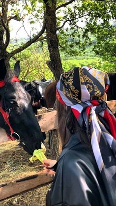 a woman wearing a bandana standing next to a horse