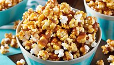 two bowls filled with caramel popcorn on top of a blue cloth next to another bowl