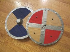 two round wooden boards with metal rivets on the top and one is painted red, white and blue