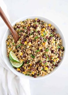 a bowl filled with rice, beans and avocado next to a wooden spoon