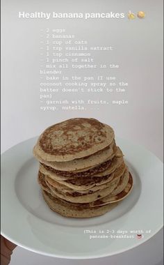 a white plate topped with lots of pancakes on top of a wooden table next to a phone