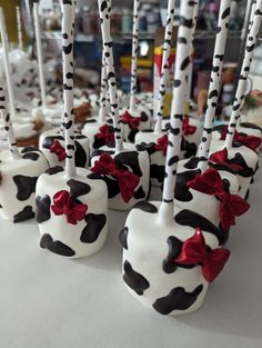 chocolate covered apples with red bows on them sitting in front of other desserts and candies