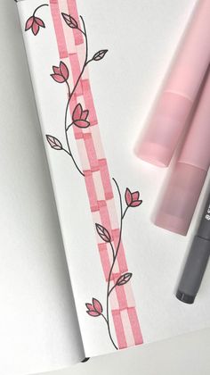 some pink pens are laying on top of a piece of paper with a checkered design