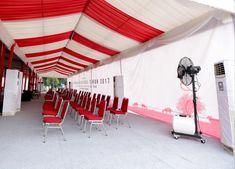 red and white chairs are lined up under a tent