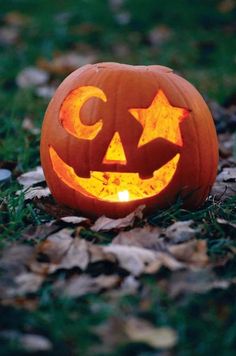 a carved pumpkin sitting on the ground with its eyes open and glowing in the dark