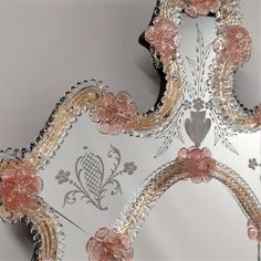 an ornate mirror with pink flowers on the edge and silver trimmings around it