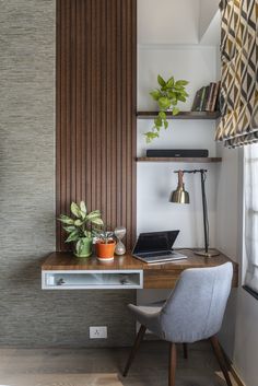 a desk with a laptop on top of it next to a plant and bookshelf