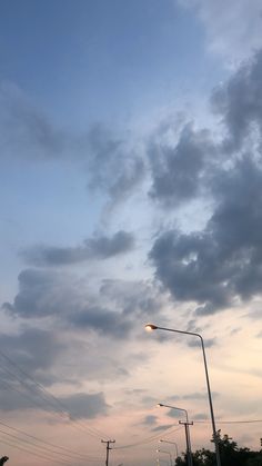 the sky is very cloudy and there are street lights in the foreground with power lines on either side