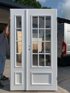 a man standing next to a white double door with windows on the outside and inside